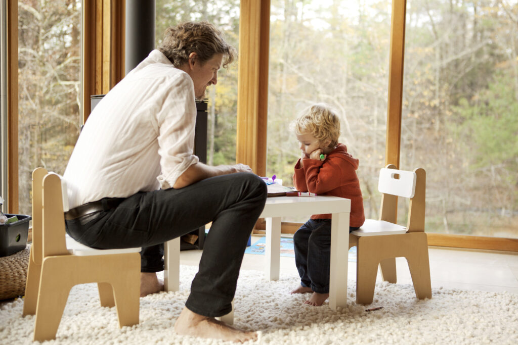 Father And Son Sitting On Chairs At Home